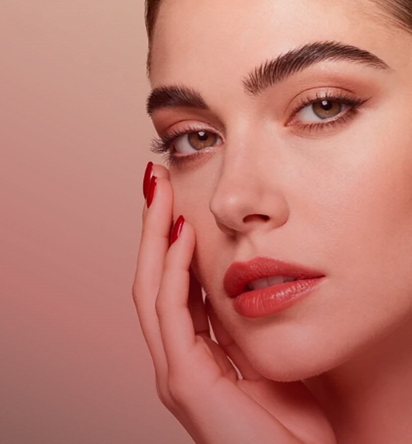 Mujer con cejas definidas y uñas color cereza